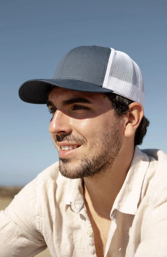 Mesh trucker cap being worn by a man on a beach